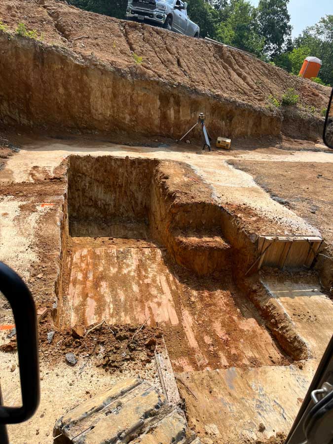 Stepped footing excavation cut into a slope for a basement foundation, seen from the excavator: driveway and foundation excavation by Rooney Excavating of Seymour, TN