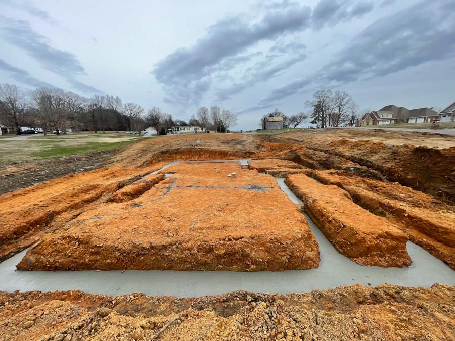 Foundation footing trenches with fresh concrete poured, on a lot in a residential subdivision: driveway and foundation excavation by Rooney Excavating of Seymour, TN