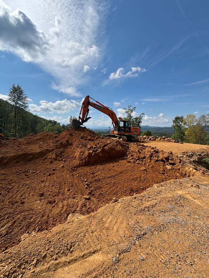 Excavator working atop a large soil mound on a mountain building site: site preparation by Rooney Excavating of Seymour, TN