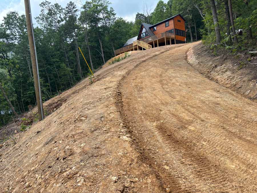 Graded dirt access road climbing a wooded hillside to a cabin: driveway and foundation excavation by Rooney Excavating of Seymour, TN