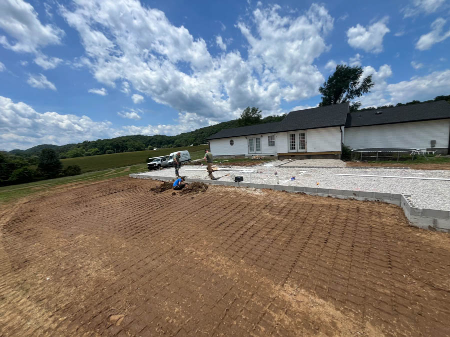 Yard graded around a single-story home with a new concrete slab, a crew member on site: residential excavation by Rooney Excavating of Seymour, TN