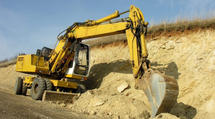 Heavy Equipment Slope Stabilization and Earthmoving A large yellow wheeled excavator actively digging and shaping a steep earthen slope under a clear blue sky, demonstrating powerful earthmoving capability.